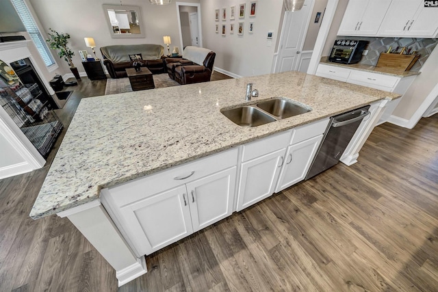 kitchen featuring sink, a kitchen island with sink, white cabinetry, light stone countertops, and stainless steel dishwasher