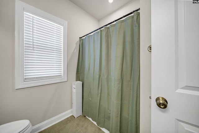 bathroom with curtained shower, tile patterned floors, and toilet