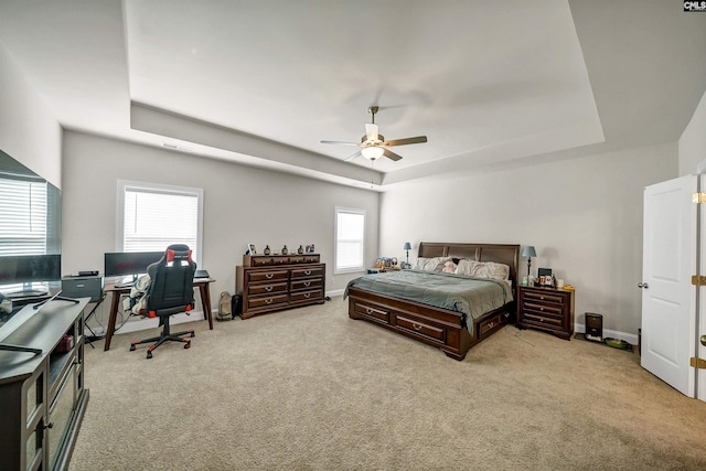 carpeted bedroom featuring ceiling fan and a raised ceiling