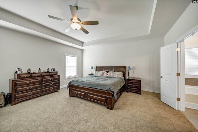 bedroom with light carpet, a raised ceiling, and ceiling fan