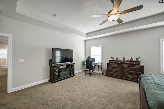 carpeted bedroom featuring ceiling fan and a tray ceiling