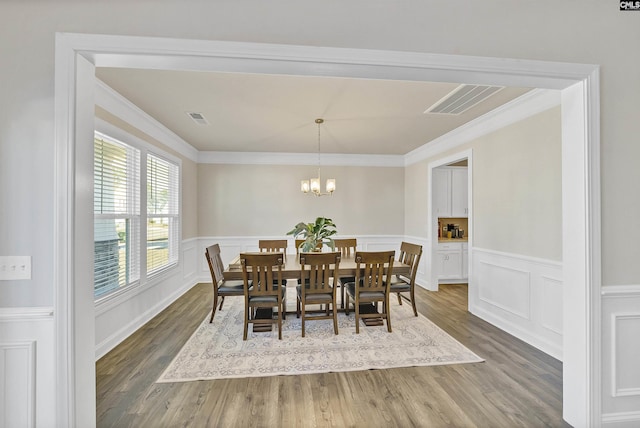 dining area with ornamental molding, a chandelier, and dark hardwood / wood-style flooring