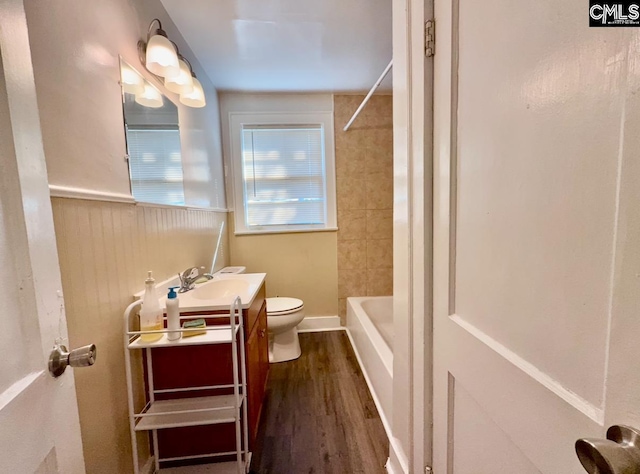 full bathroom with hardwood / wood-style flooring, vanity, tiled shower / bath combo, and toilet