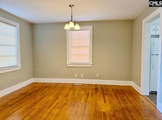 unfurnished room featuring hardwood / wood-style floors and a notable chandelier