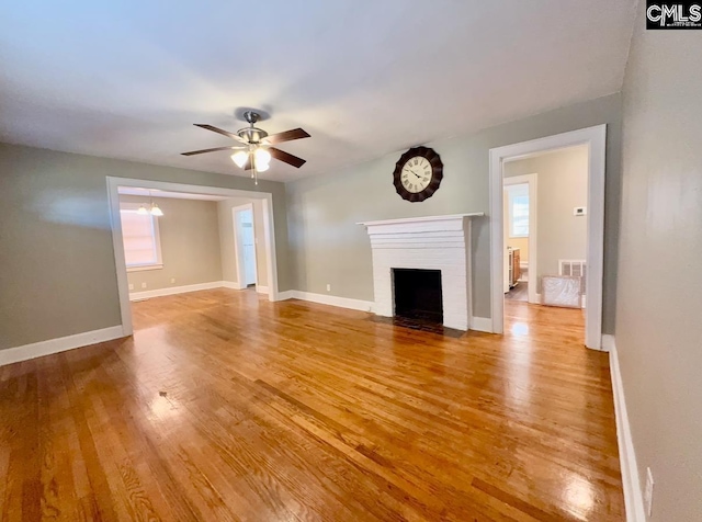 unfurnished living room featuring ceiling fan, a brick fireplace, and light hardwood / wood-style flooring