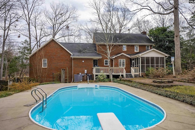 view of pool with central AC, a sunroom, a diving board, and a deck