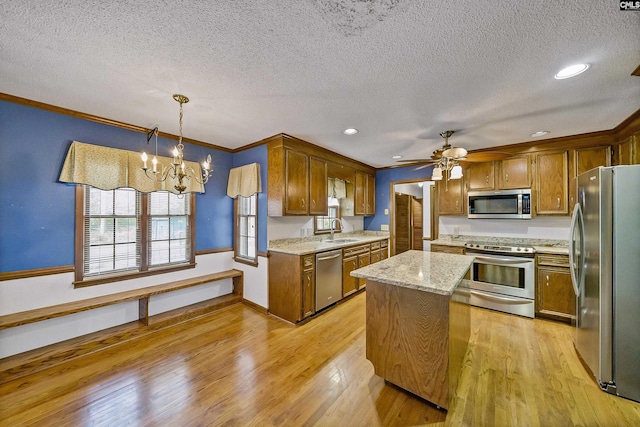 kitchen featuring a kitchen island, appliances with stainless steel finishes, sink, hanging light fixtures, and crown molding