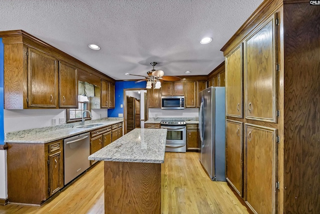 kitchen with sink, light hardwood / wood-style flooring, light stone countertops, and appliances with stainless steel finishes