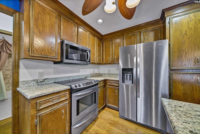 kitchen with stainless steel appliances, ceiling fan, light stone countertops, and light wood-type flooring