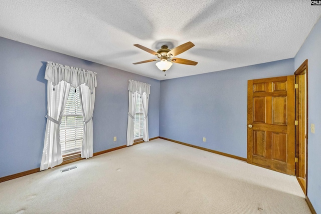 empty room featuring a textured ceiling, light colored carpet, and ceiling fan