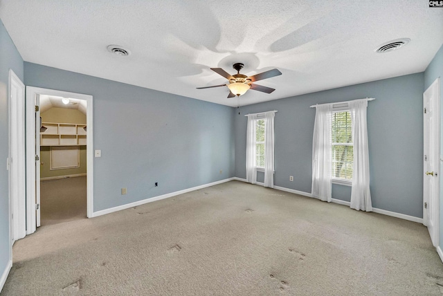 carpeted spare room with ceiling fan and a textured ceiling