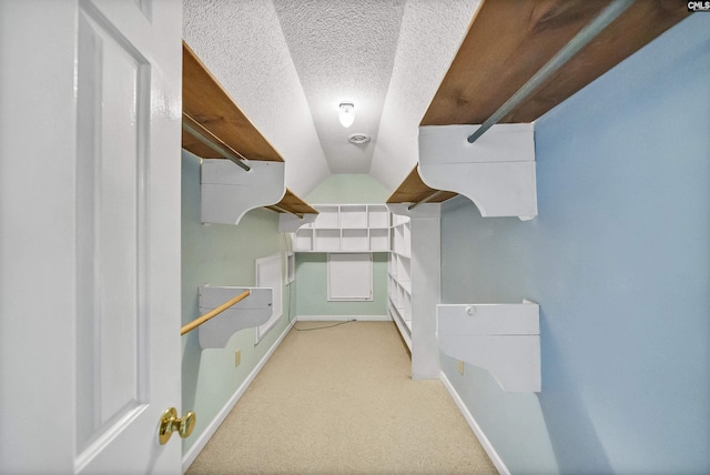 walk in closet featuring vaulted ceiling and light carpet