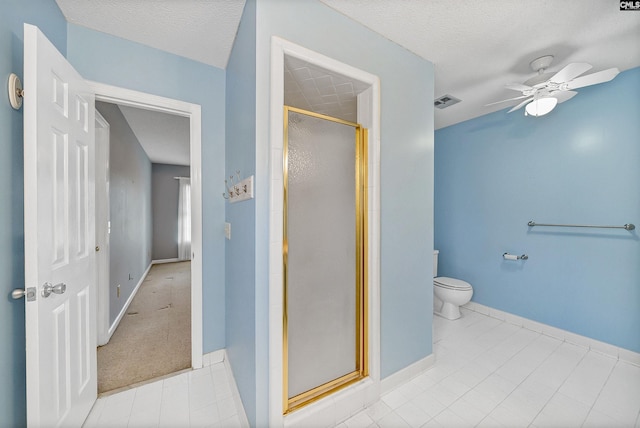 bathroom featuring a shower with shower door, ceiling fan, toilet, tile patterned floors, and a textured ceiling