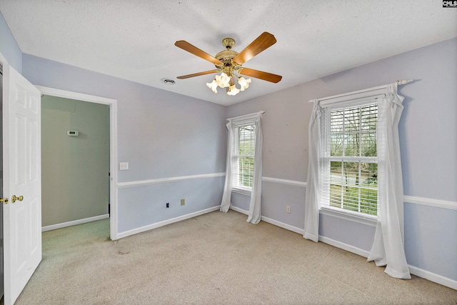 unfurnished room featuring ceiling fan, light colored carpet, and a textured ceiling