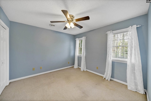 unfurnished bedroom with ceiling fan, light carpet, a textured ceiling, and a closet