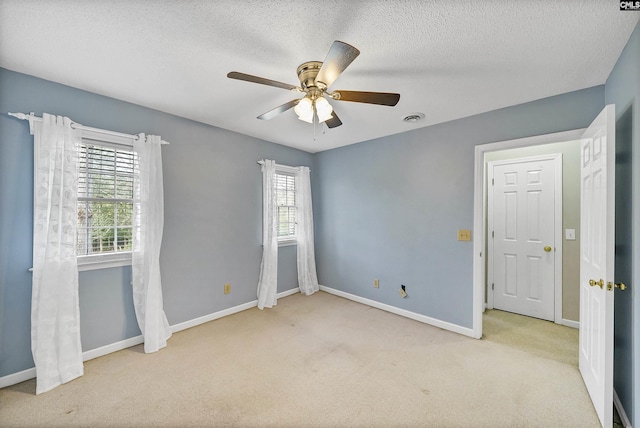 spare room with ceiling fan, light colored carpet, and a textured ceiling