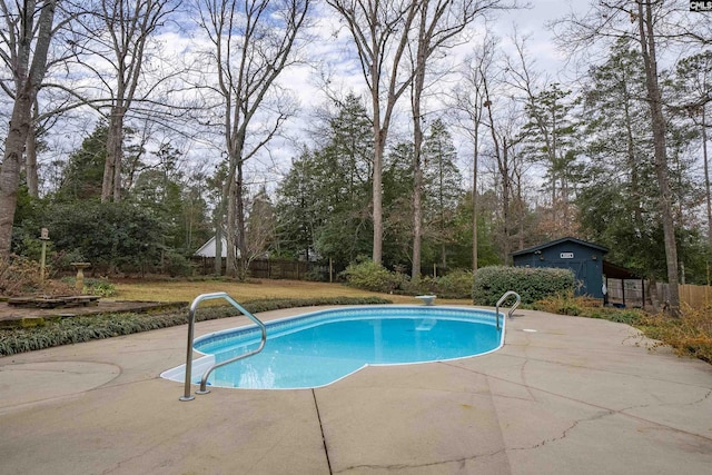 view of swimming pool featuring an outbuilding, a patio area, and a diving board