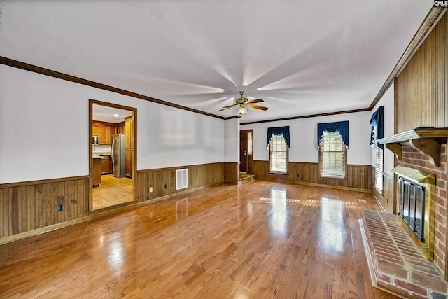 living room featuring a fireplace, light hardwood / wood-style floors, ceiling fan, and wood walls