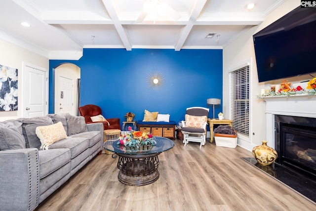 living room featuring hardwood / wood-style flooring, a fireplace, crown molding, and beamed ceiling