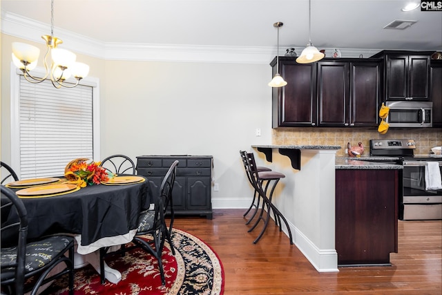 kitchen featuring light stone counters, stainless steel appliances, hanging light fixtures, and backsplash