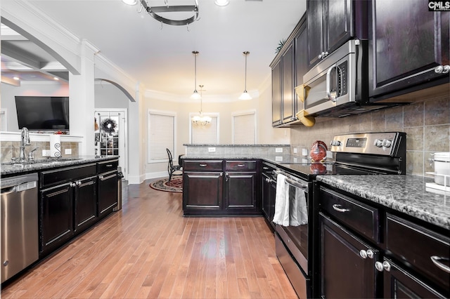 kitchen with light stone countertops, appliances with stainless steel finishes, sink, and pendant lighting