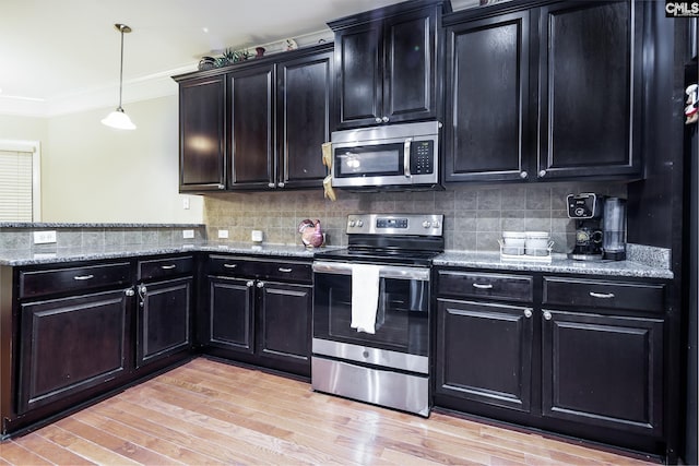 kitchen featuring decorative light fixtures, decorative backsplash, ornamental molding, and appliances with stainless steel finishes