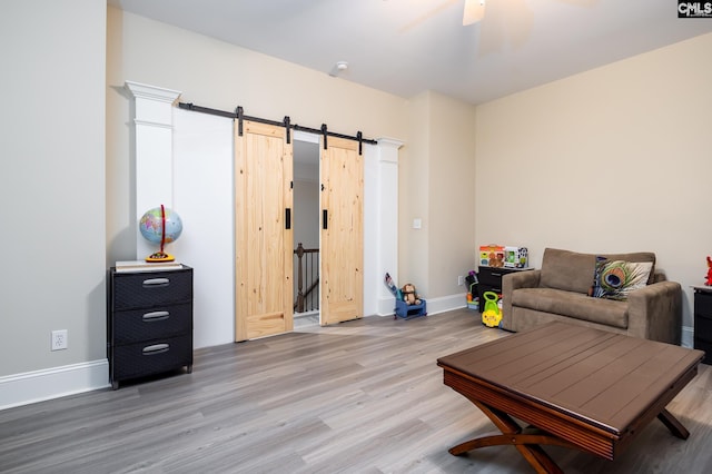 sitting room featuring hardwood / wood-style flooring, a barn door, and ceiling fan