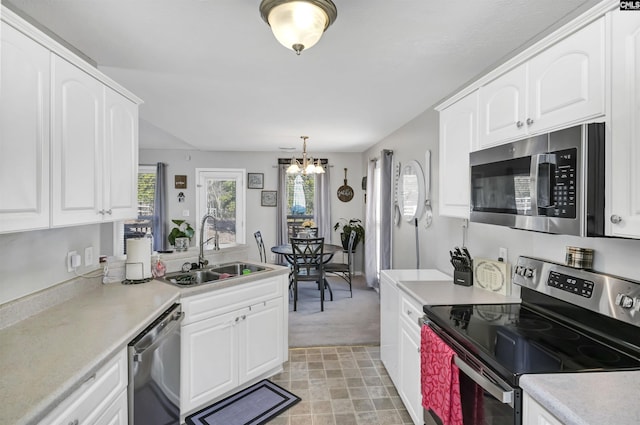 kitchen featuring sink, white cabinets, hanging light fixtures, a notable chandelier, and stainless steel appliances