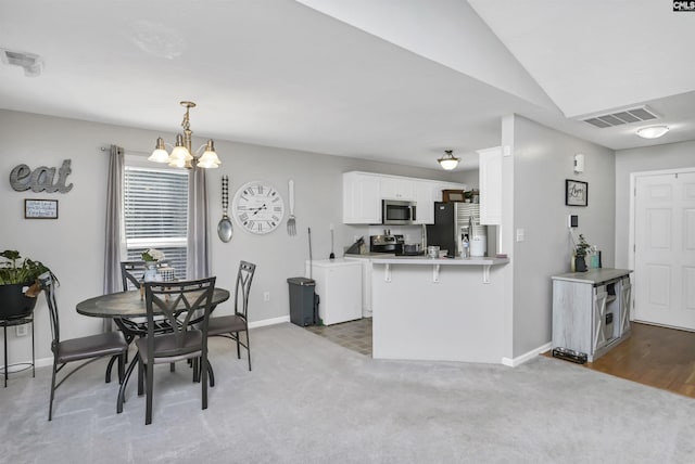 dining room featuring lofted ceiling, light carpet, and a chandelier