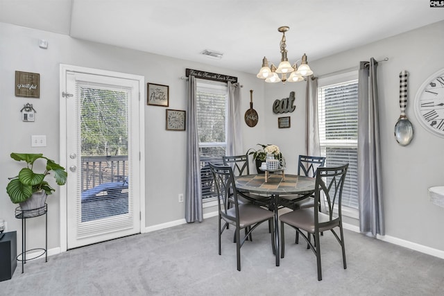 carpeted dining space with an inviting chandelier