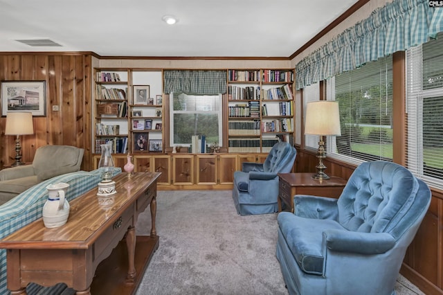 sitting room featuring crown molding, light colored carpet, built in shelves, and wood walls