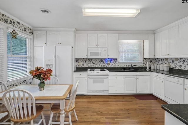 kitchen featuring plenty of natural light, sink, white cabinets, and white appliances