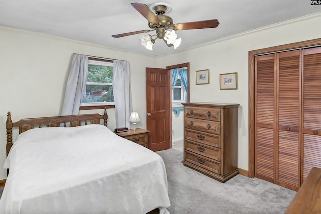 carpeted bedroom with ornamental molding, ceiling fan, and a closet