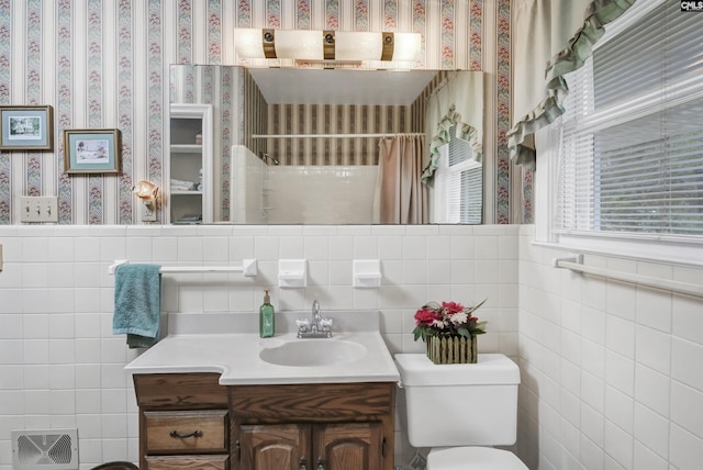 bathroom with vanity, toilet, a shower with shower curtain, and tile walls