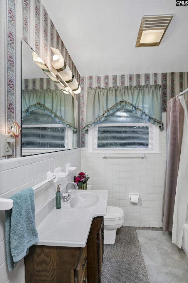 bathroom featuring vanity, toilet, and tile walls