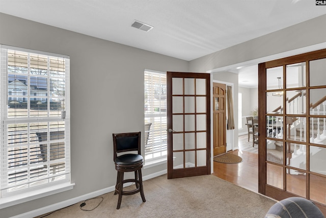 sitting room featuring light carpet and french doors