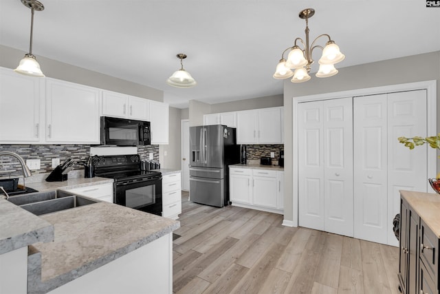 kitchen featuring hanging light fixtures, white cabinets, and black appliances