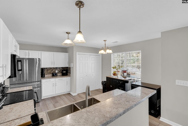 kitchen with white cabinetry, decorative backsplash, sink, and hanging light fixtures