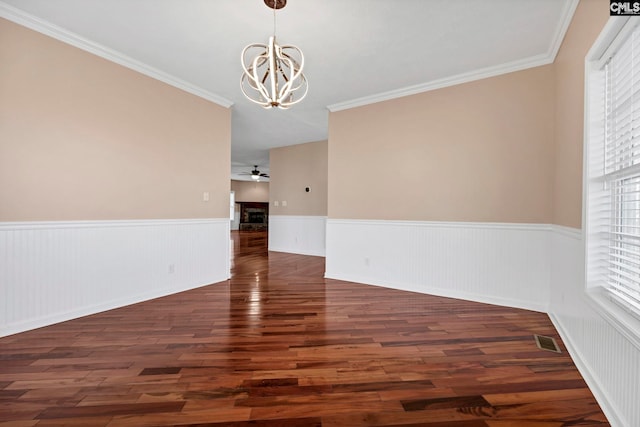 spare room with crown molding, ceiling fan with notable chandelier, and dark hardwood / wood-style floors