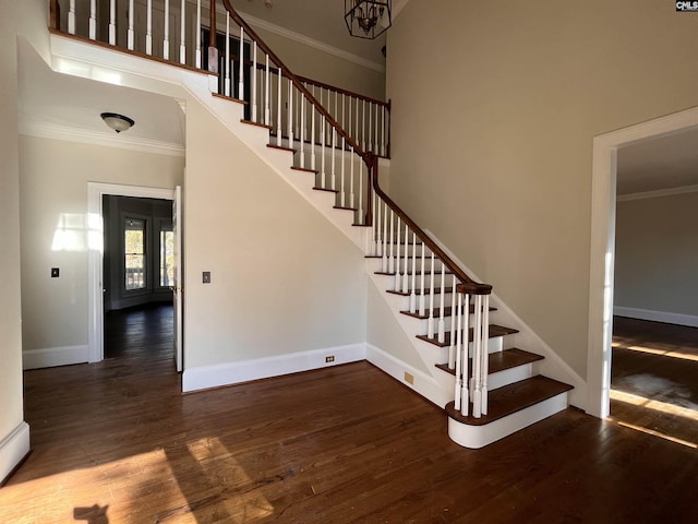 stairway featuring hardwood / wood-style flooring, ornamental molding, and a high ceiling