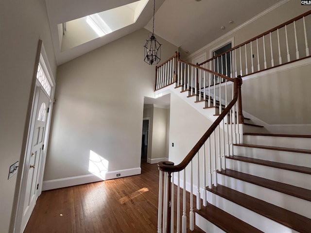 stairway featuring hardwood / wood-style flooring, crown molding, a chandelier, and high vaulted ceiling