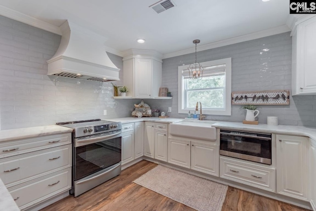 kitchen featuring stainless steel electric range oven, decorative light fixtures, white cabinetry, sink, and custom range hood