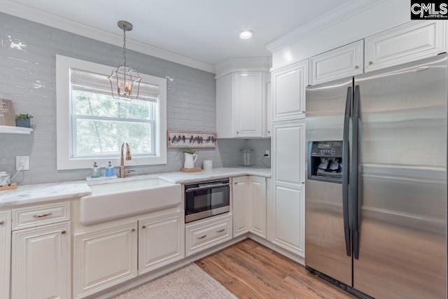 kitchen featuring white cabinetry, sink, pendant lighting, and stainless steel fridge