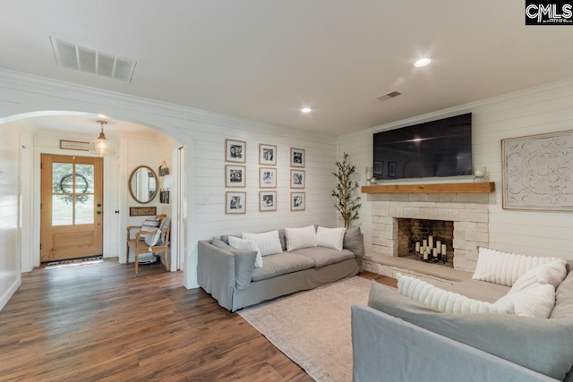 living room featuring hardwood / wood-style flooring, ornamental molding, and a fireplace