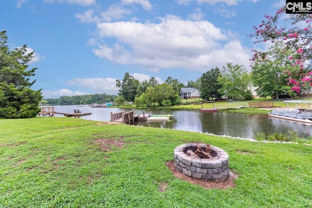 view of yard with a water view, a dock, and a fire pit