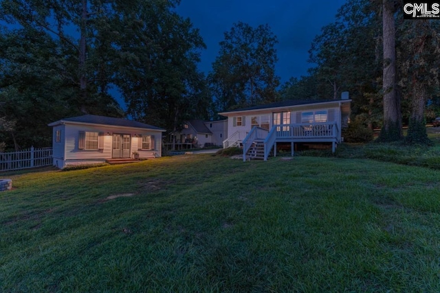 back of property with a wooden deck and a lawn