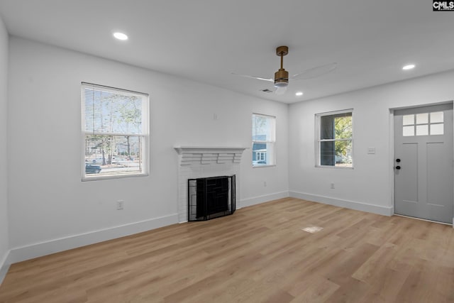 unfurnished living room with ceiling fan, a fireplace, and light hardwood / wood-style flooring