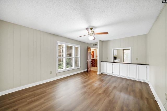 unfurnished room with a textured ceiling, wood-type flooring, and ceiling fan