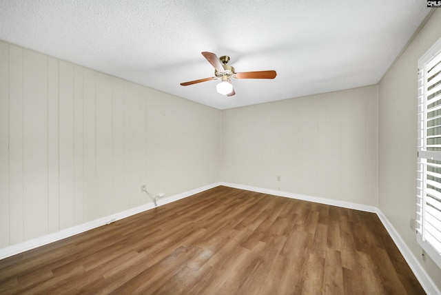 empty room with ceiling fan, hardwood / wood-style flooring, and a textured ceiling