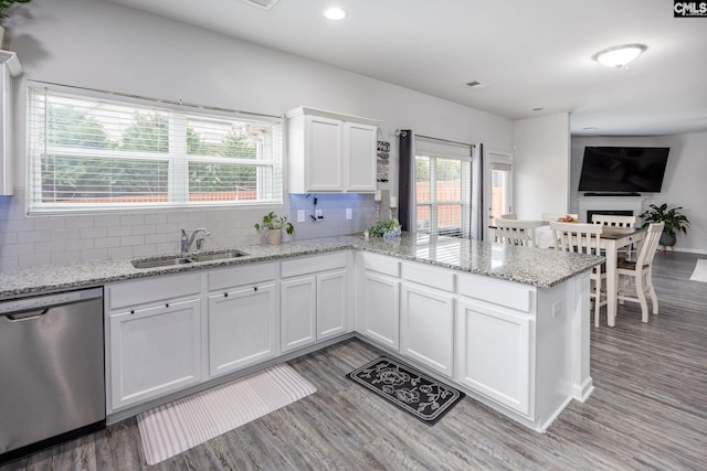 kitchen with tasteful backsplash, white cabinetry, dishwasher, sink, and kitchen peninsula